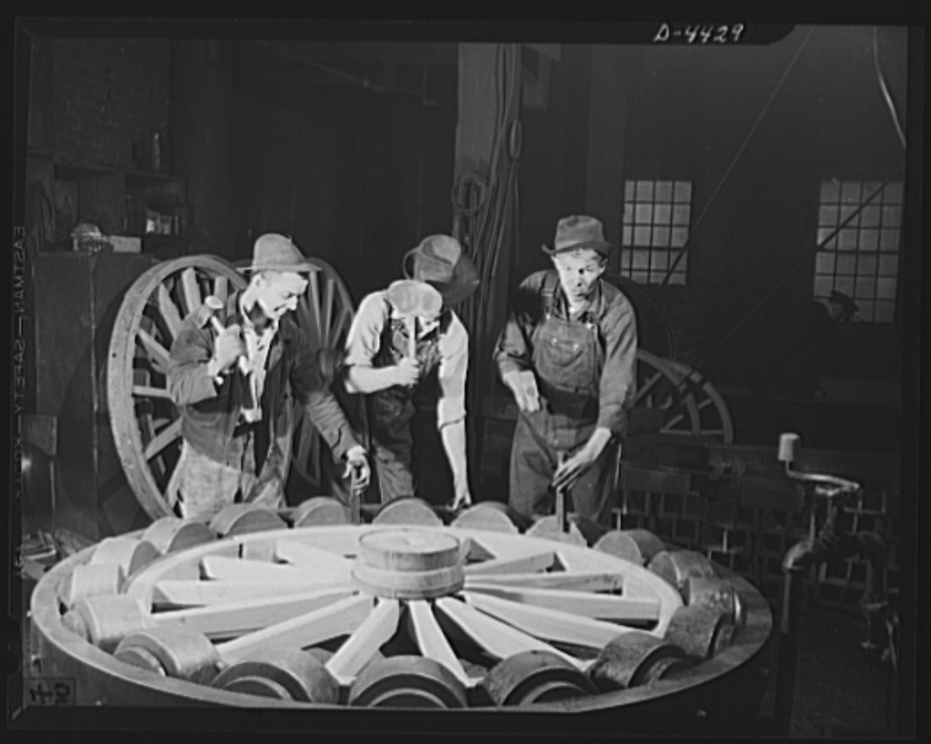 Workers fit a hot steel tire onto a wooden wagon wheel, 1942